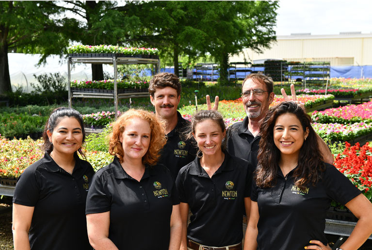 Newton Nurseries' Employees Smiling In Front Of Flowers